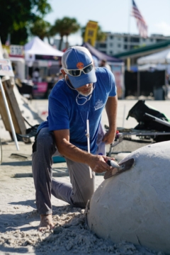 sculptor using a trowl to even out sand sculpture